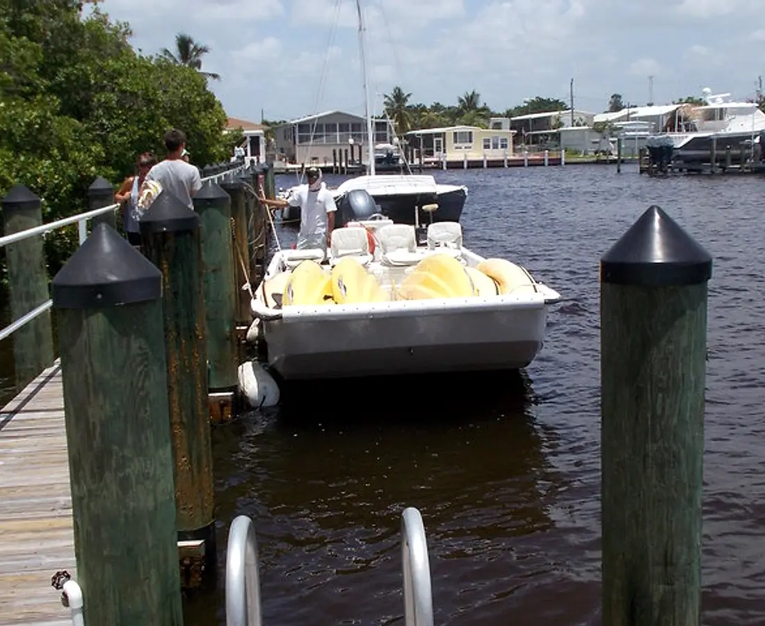 A tour boat tying up at the public dock at Goodland Boat Park, 750 Palm Point Dr, Goodland, Florida, with the village and its boat lifts across the channel