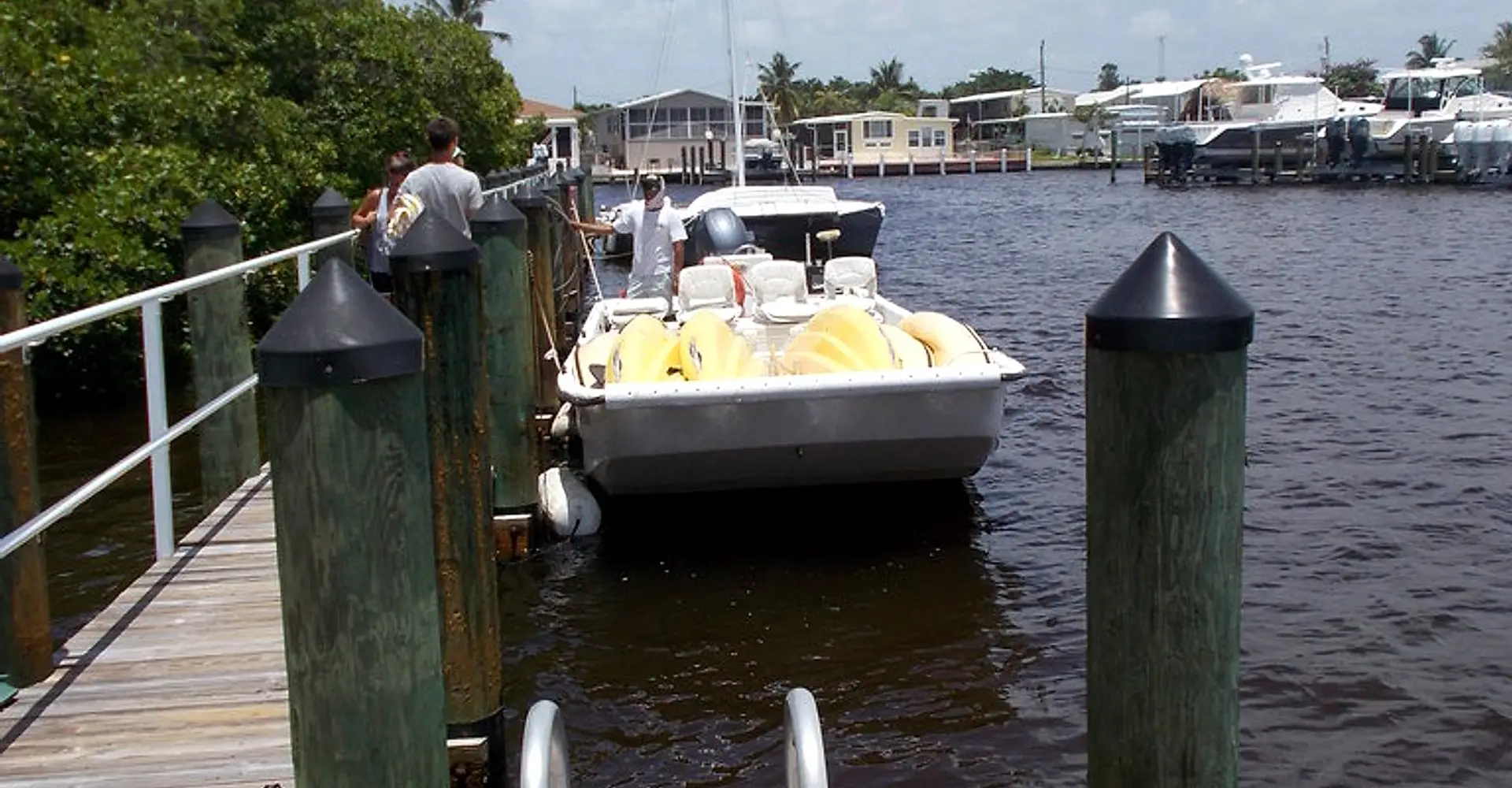 A tour boat tying up at the public dock at Goodland Boat Park, 750 Palm Point Dr, Goodland, Florida, with the village and its boat lifts across the channel