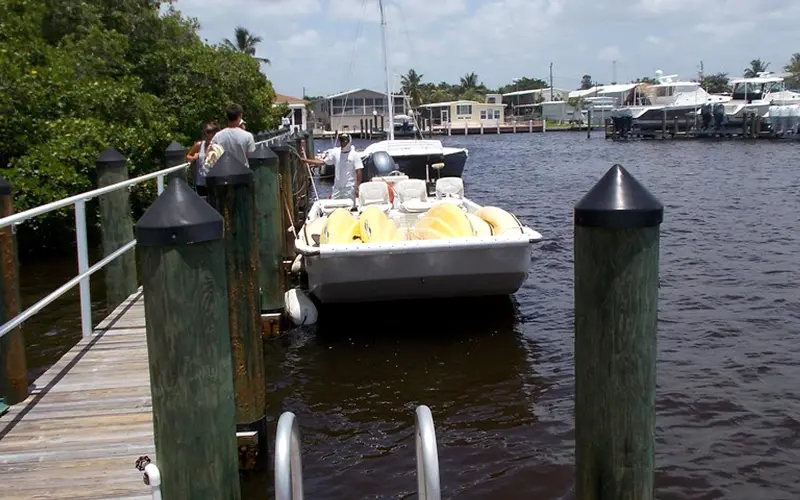 A tour boat tying up at the public dock at Goodland Boat Park, 750 Palm Point Dr, Goodland, Florida, with the village and its boat lifts across the channel